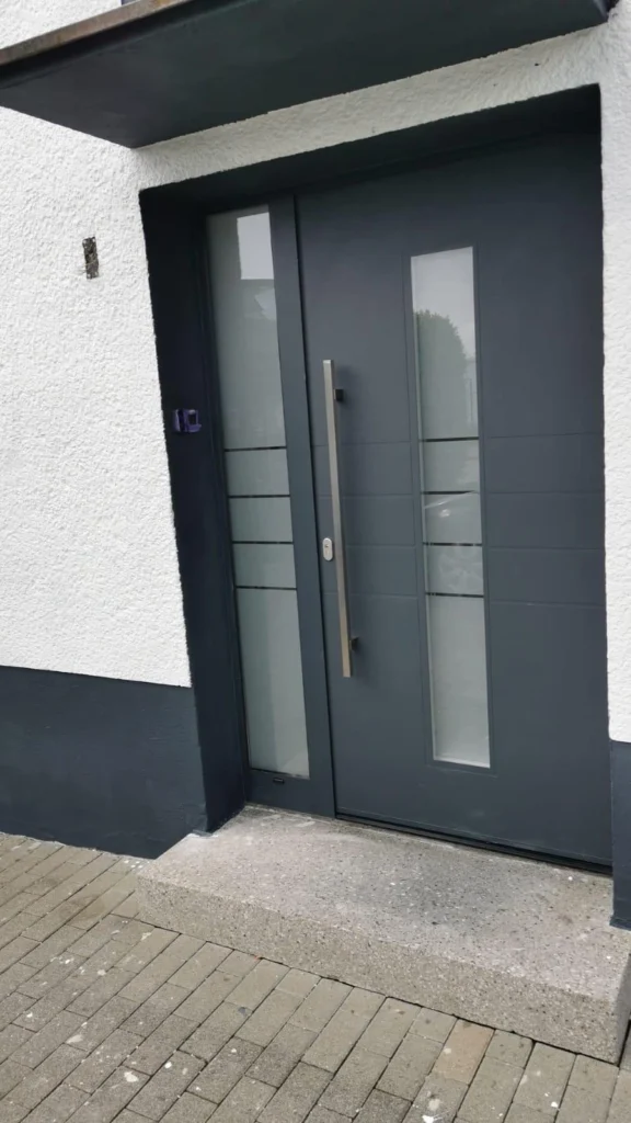 Anthrazitfarbene Haustür mit Glaseinsätzen an einem weißen Wohnhaus