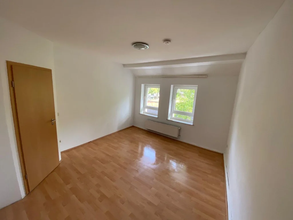 Leerer, besenreiner Raum mit Laminatboden und Doppelfenster