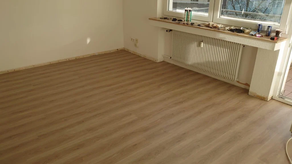 Heller, leerer Raum mit neuem Laminatboden unter dem Fenster