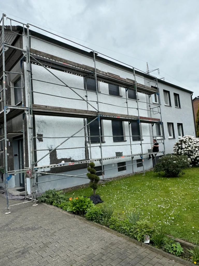 Gerüst an der Fassade eines zweigeschossigen Mehrfamilienhauses