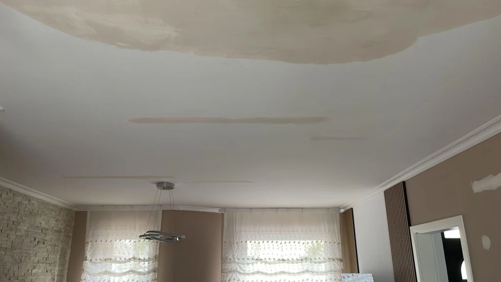 Zimmerdecke mit großem Wasserfleck über den Fenstern