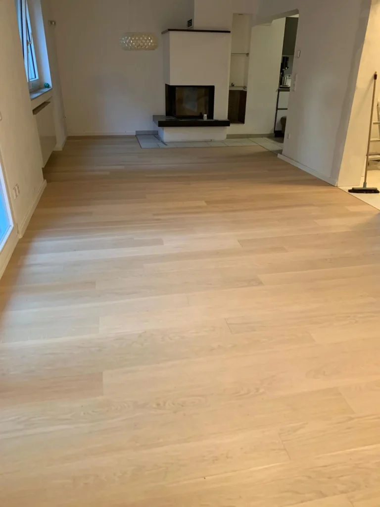 Großer Wohnraum mit neu verlegtem hellem Holzboden