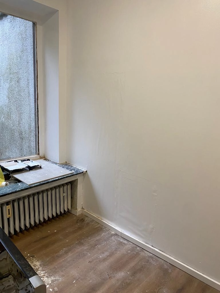 Instandgesetzter kleiner Raum mit frisch gestrichenen Wänden und Heizkörper