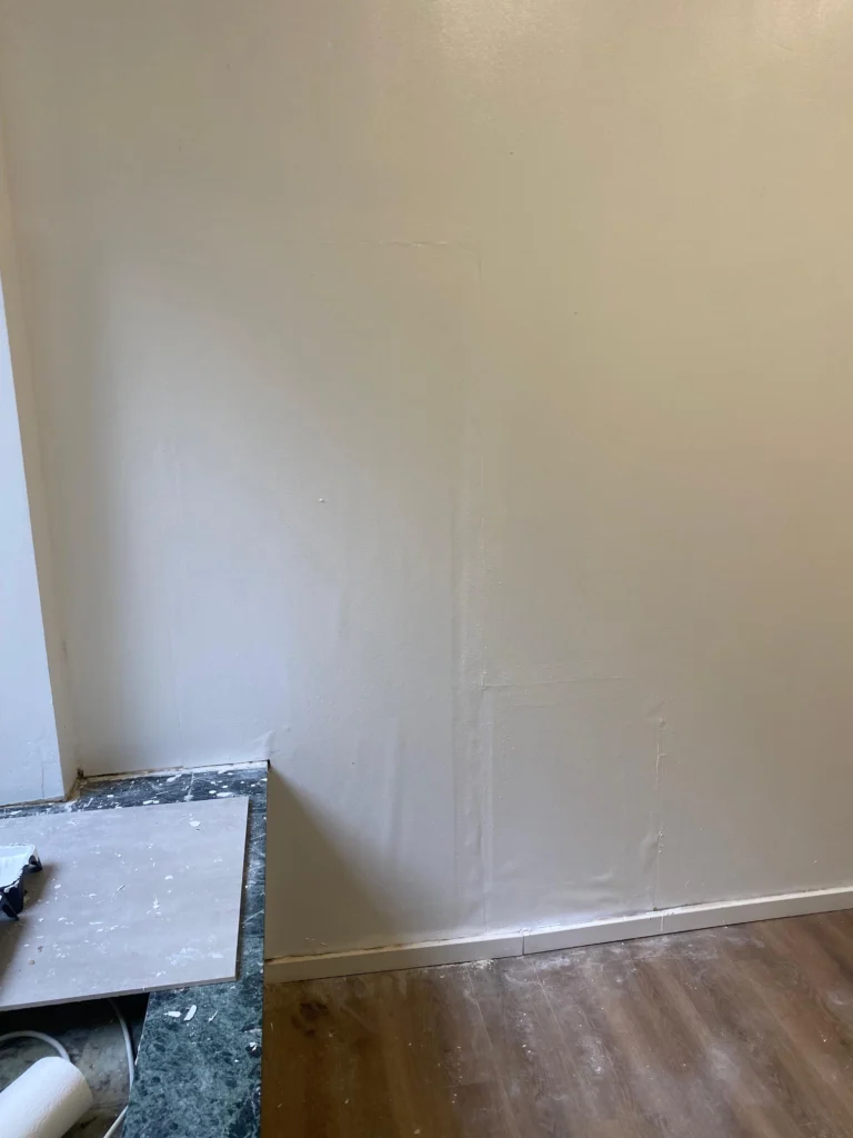 Frisch verputzte und gestrichene Wand über neuer Sockelleiste
