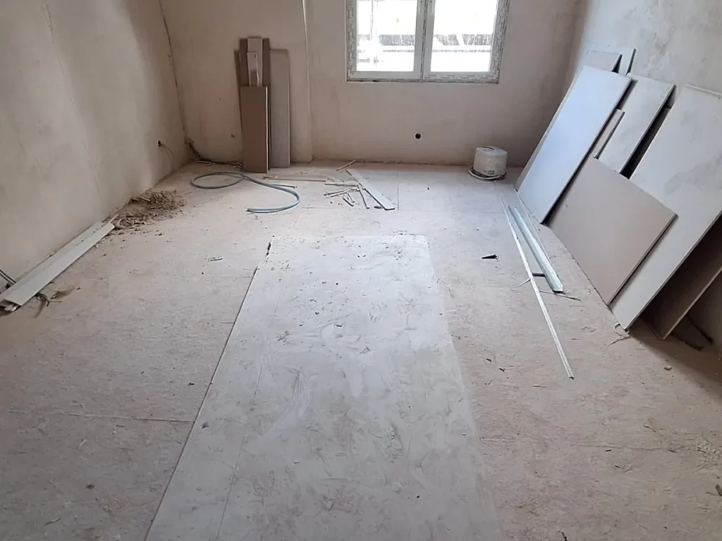 Zimmer im Rohbau nach der Entkernung, Gipskartonplatten und Leerrohre liegen bereit