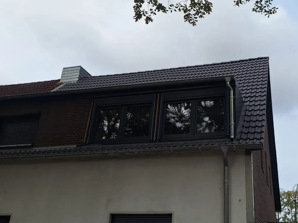 Dachgaube mit Fensterband, Dachrinne und Fallrohr an einem eingedeckten Steildach