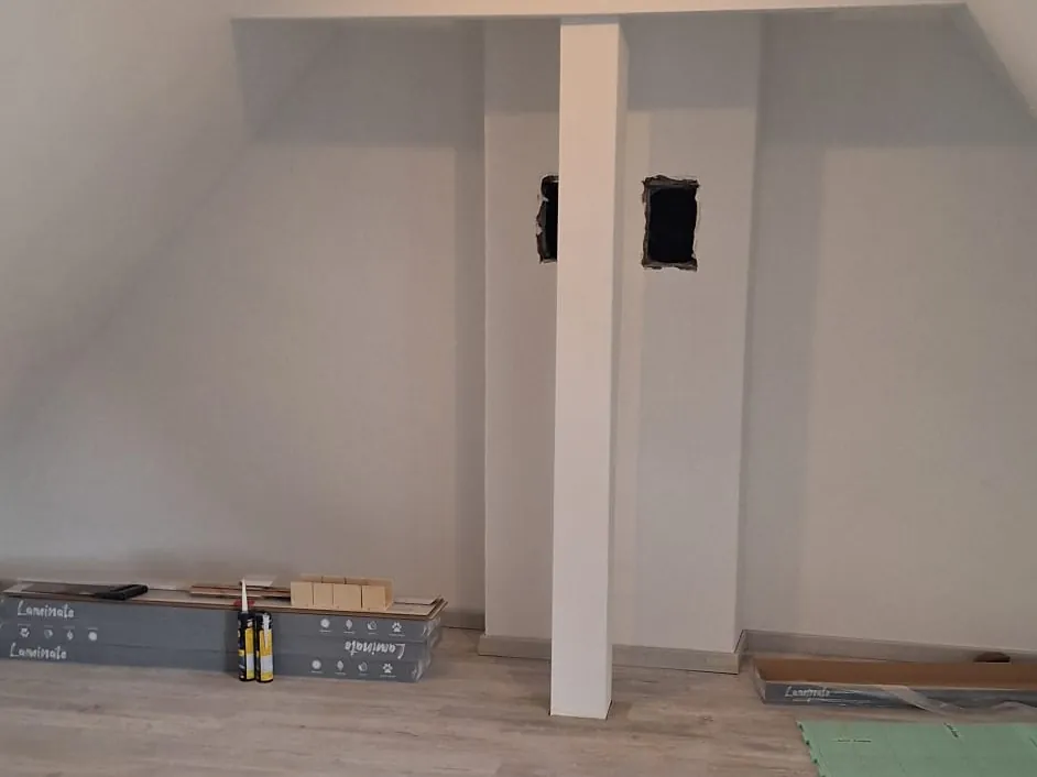 Dachgeschoss mit neu verlegtem Laminatboden in Holzoptik, Bodenpakete liegen bereit