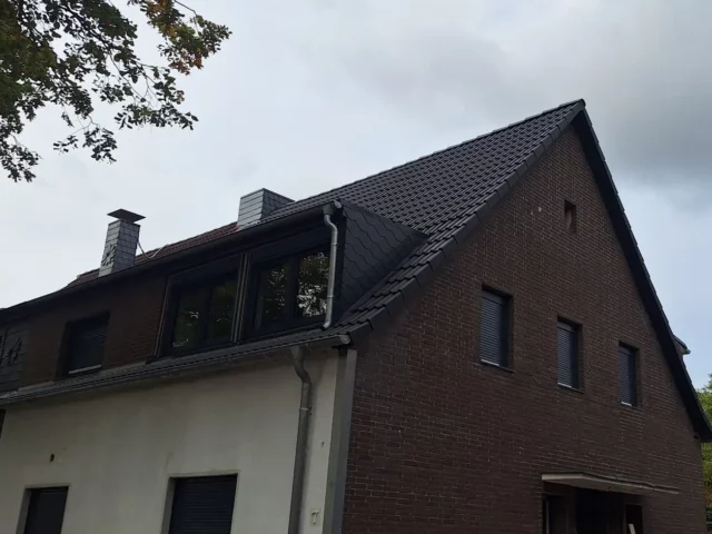 Wohnhaus mit dunkel eingedecktem Steildach und Dachgaube