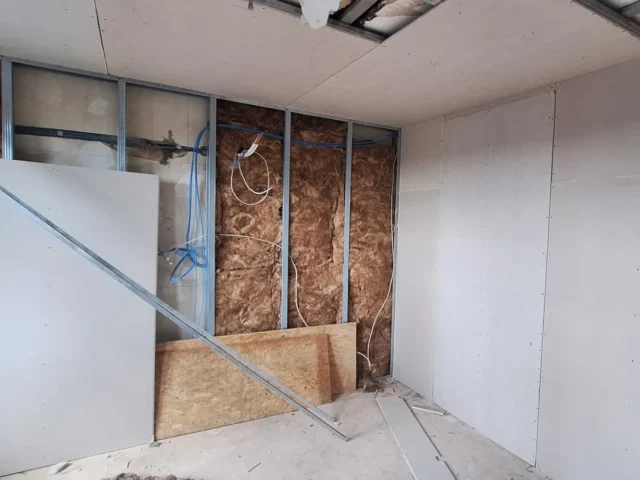 Trockenbauwand im Bau: Metallständerwerk mit Dämmung, daneben bereits beplankte Gipskartonwände