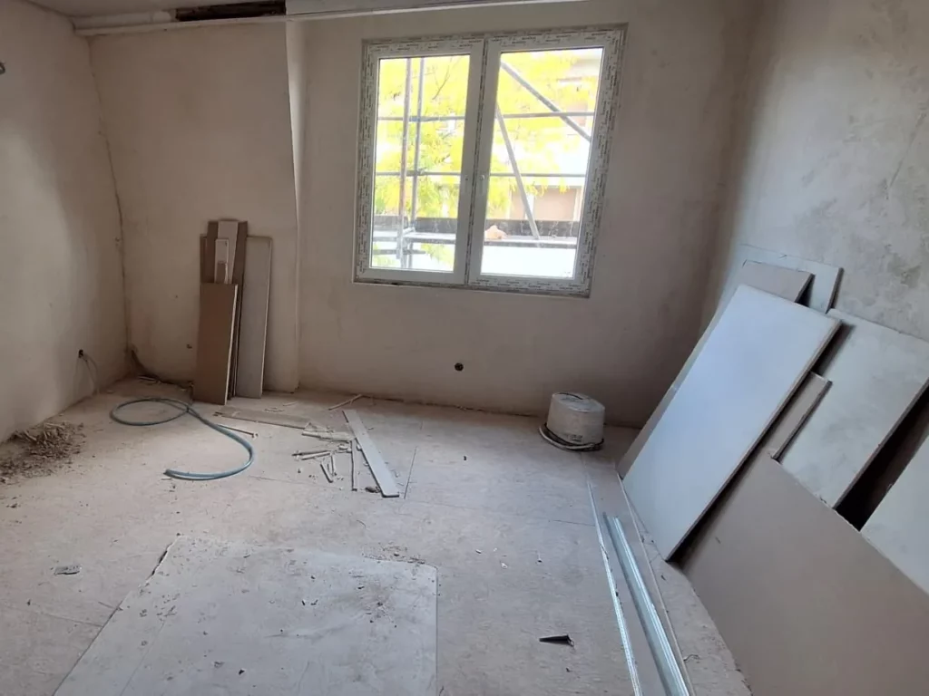 Zimmer im Innenausbau mit verspachtelten Gipskartonwänden, bereitstehenden Platten und Leerrohren am Boden