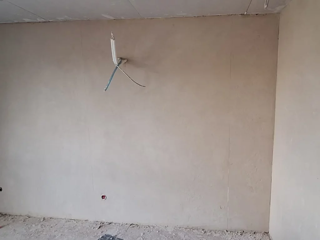 Glatt verputzte Wand mit vorbereiteten Elektrodosen und Leitungsenden