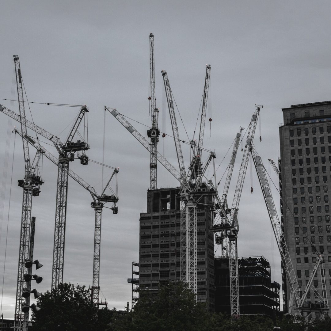 low-angle-view-cranes-against-sky-city
